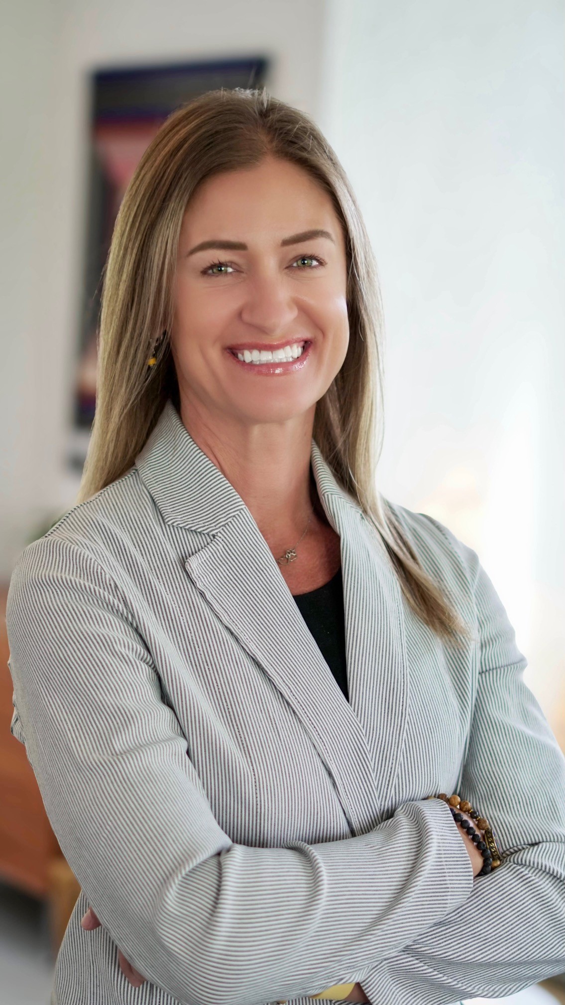 Mara Rasikas smiling in a light striped blazer